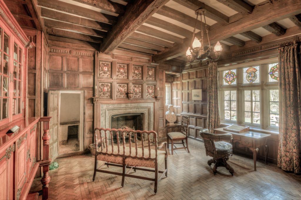 ornate period room with rafters, hearth, paneling, stained glass